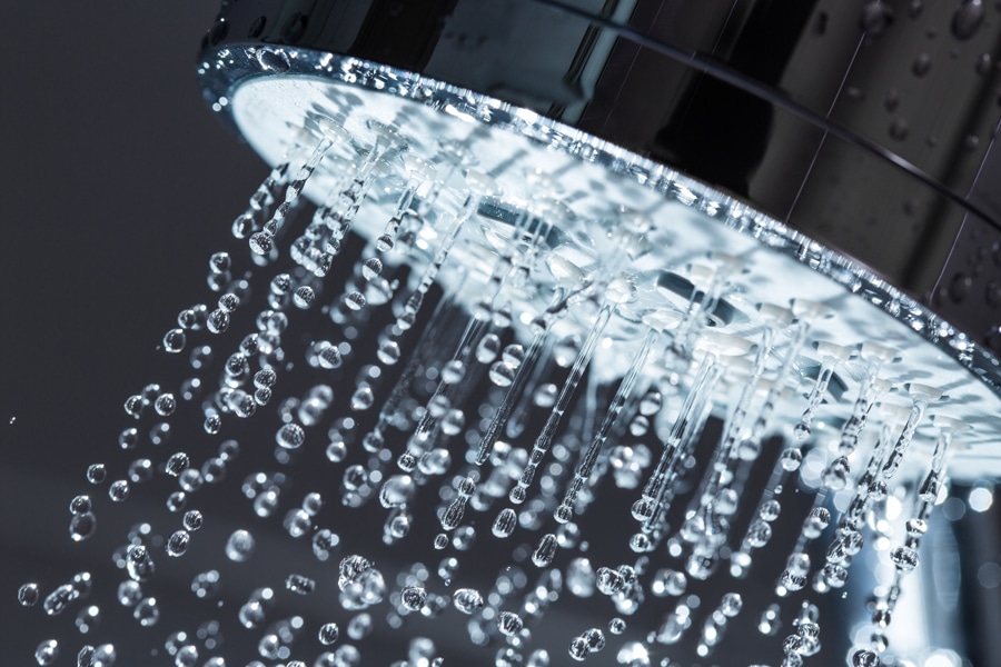 Shower Head with Water Stream on Black Background