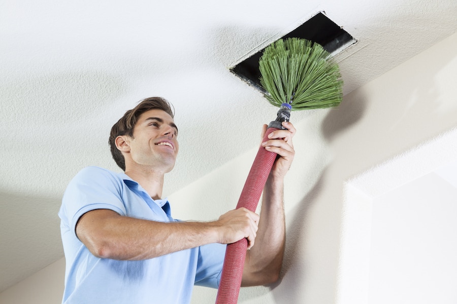 Man cleaning air ducts to eliminate dust and mold in home