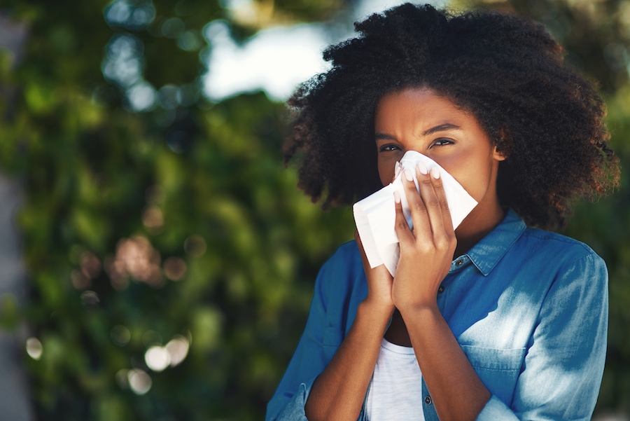 Woman blowing her nose due to not using her ac to help with allergy symptoms