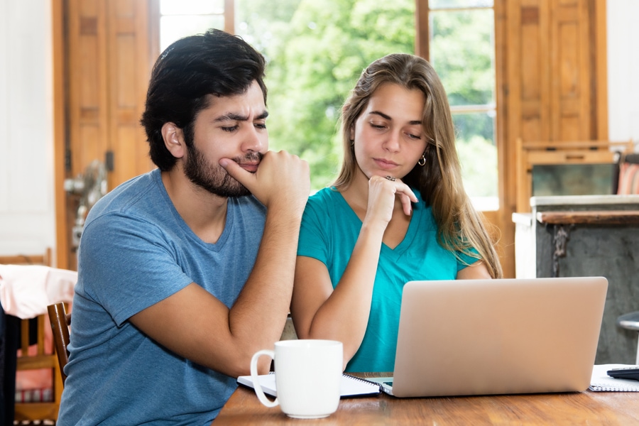homeowners sitting in front of computer trying to decide if HVAC preventative maintenance is worth it