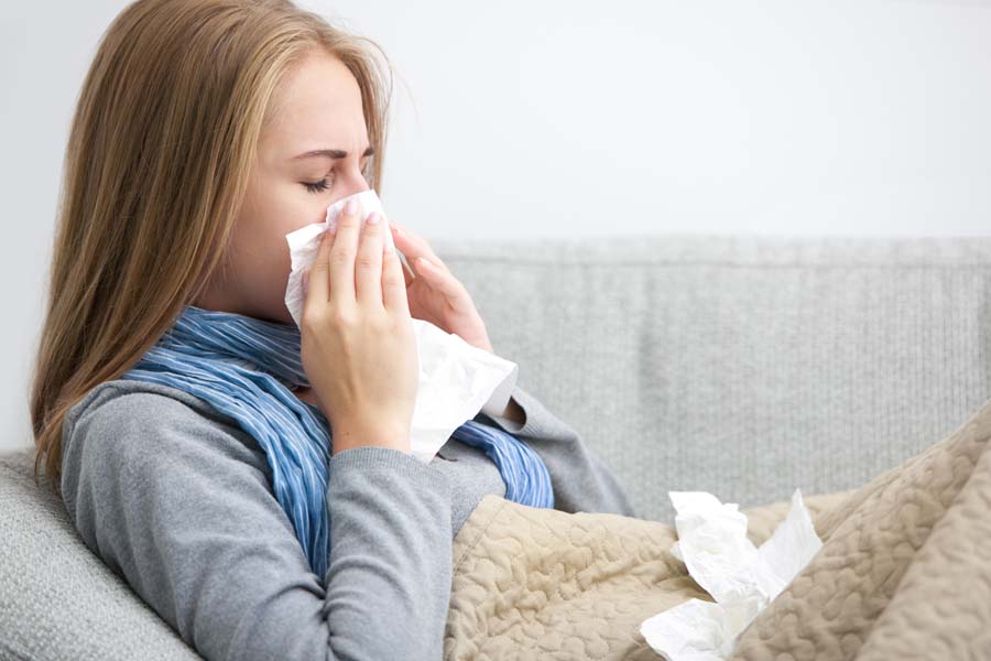 Woman blowing her nose at home wondering if her AC system really helps with allergies.