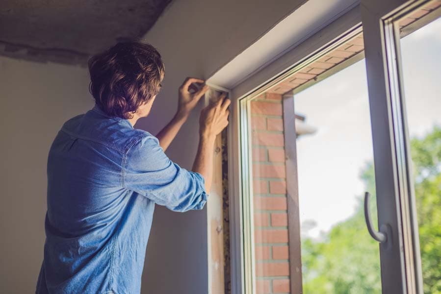 Man checking the window seal as part of the heat gain prevention tips.