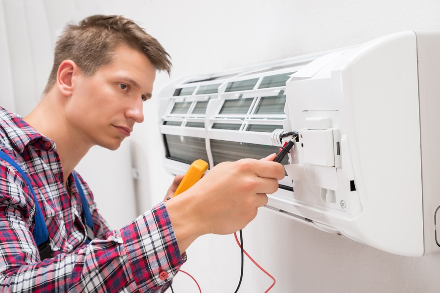 Male Technician Examining Air Conditioner With Multimeter