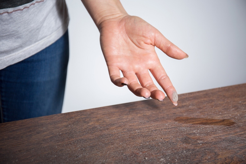 Close-up of dust on woman finger taken from wooden table, how to eliminate dust in my home